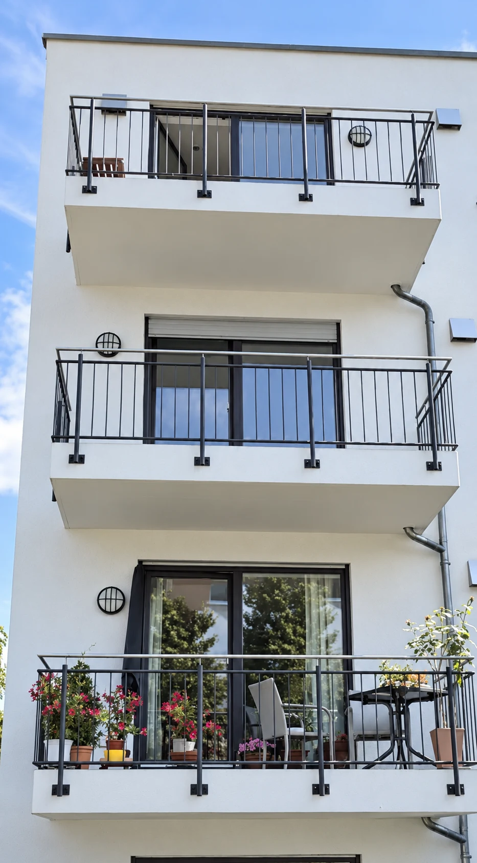 Mehrgeschossige Balkonanlage mit anthrazitfarbenen Metallgelaendern an einem Wohnhaus